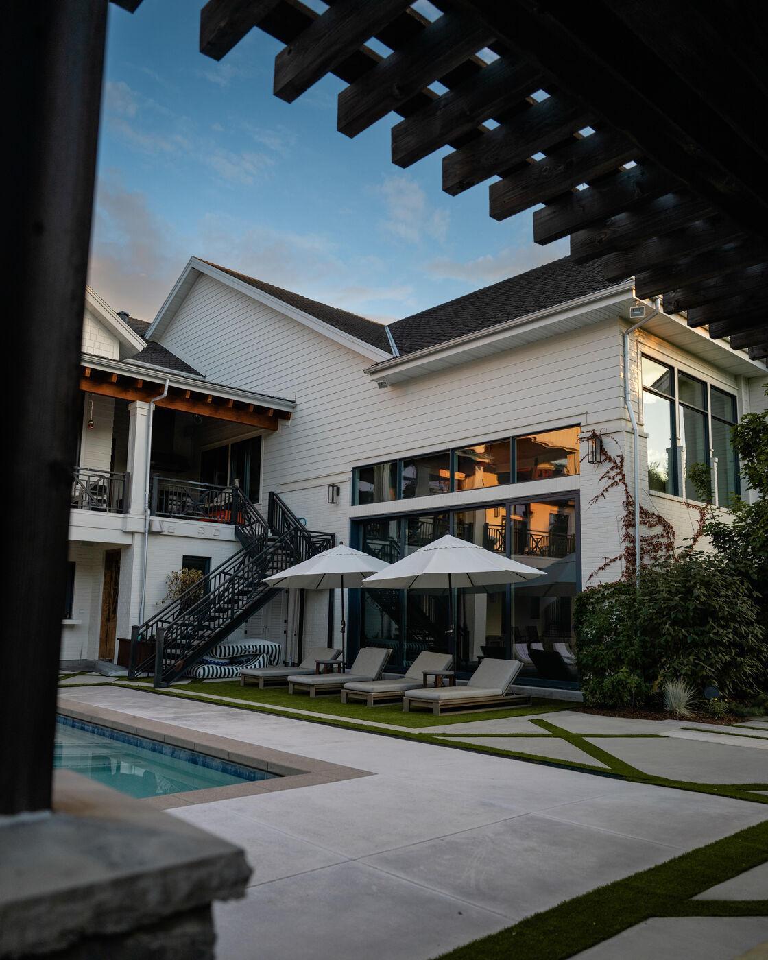 A finished concrete terrace running past the pool under a timber pergola