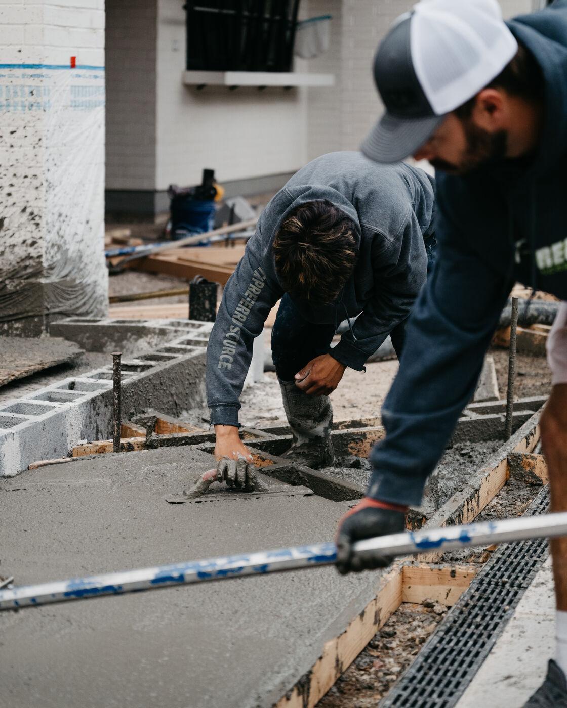 A crew member screeding a slab over reinforcing mesh