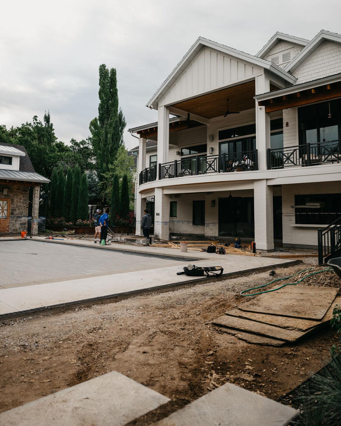 An open site with forms set and the house still under construction behind