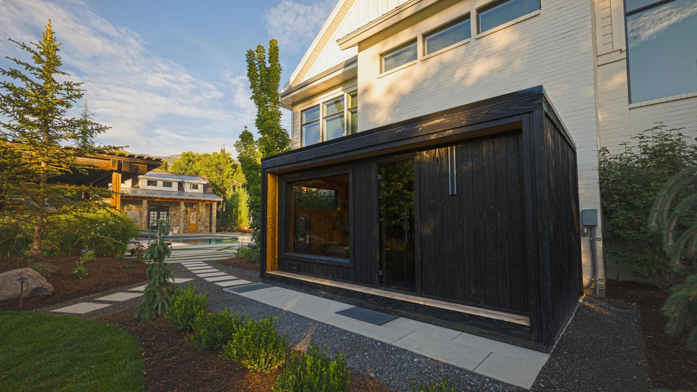 A blackened-timber studio set among conifers beside the house