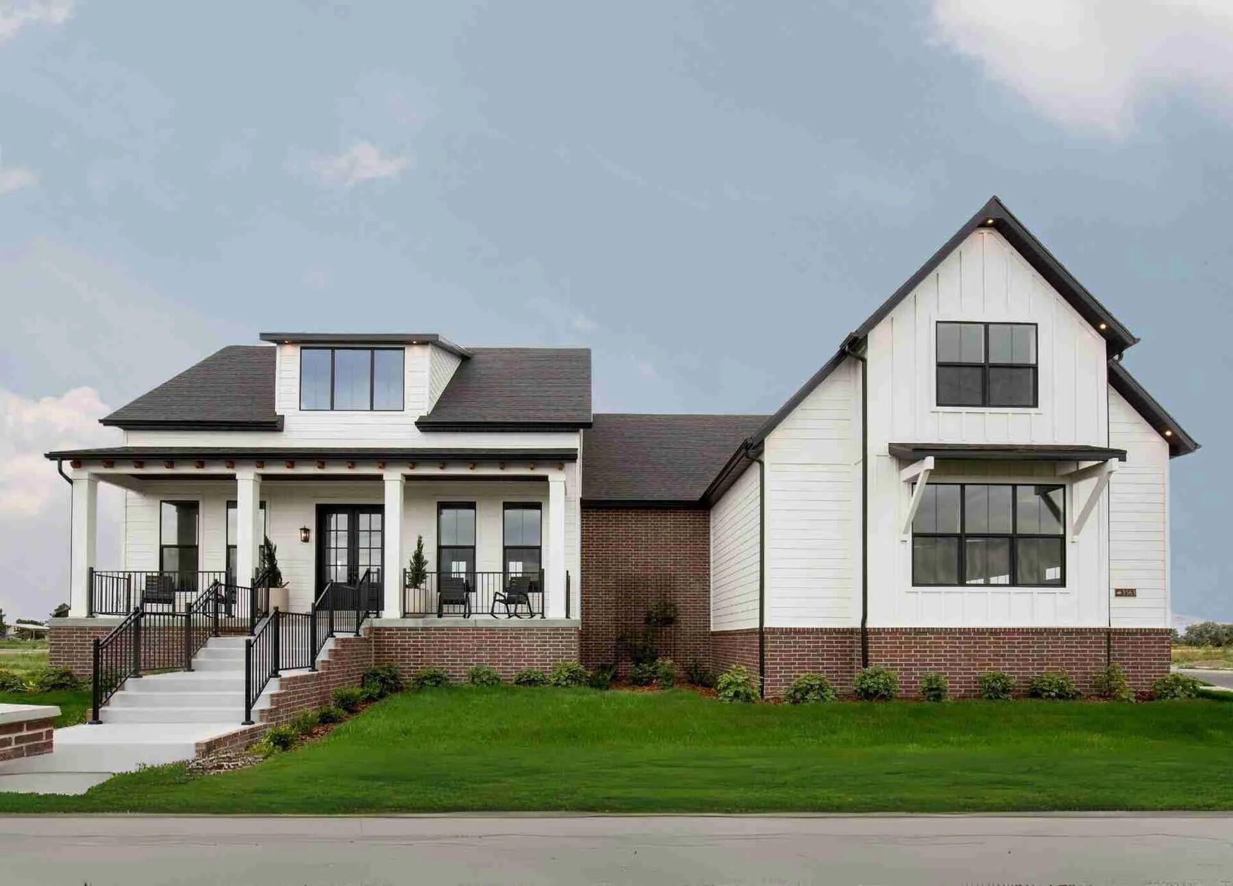 A white farmhouse elevation with new front lawn and foundation planting