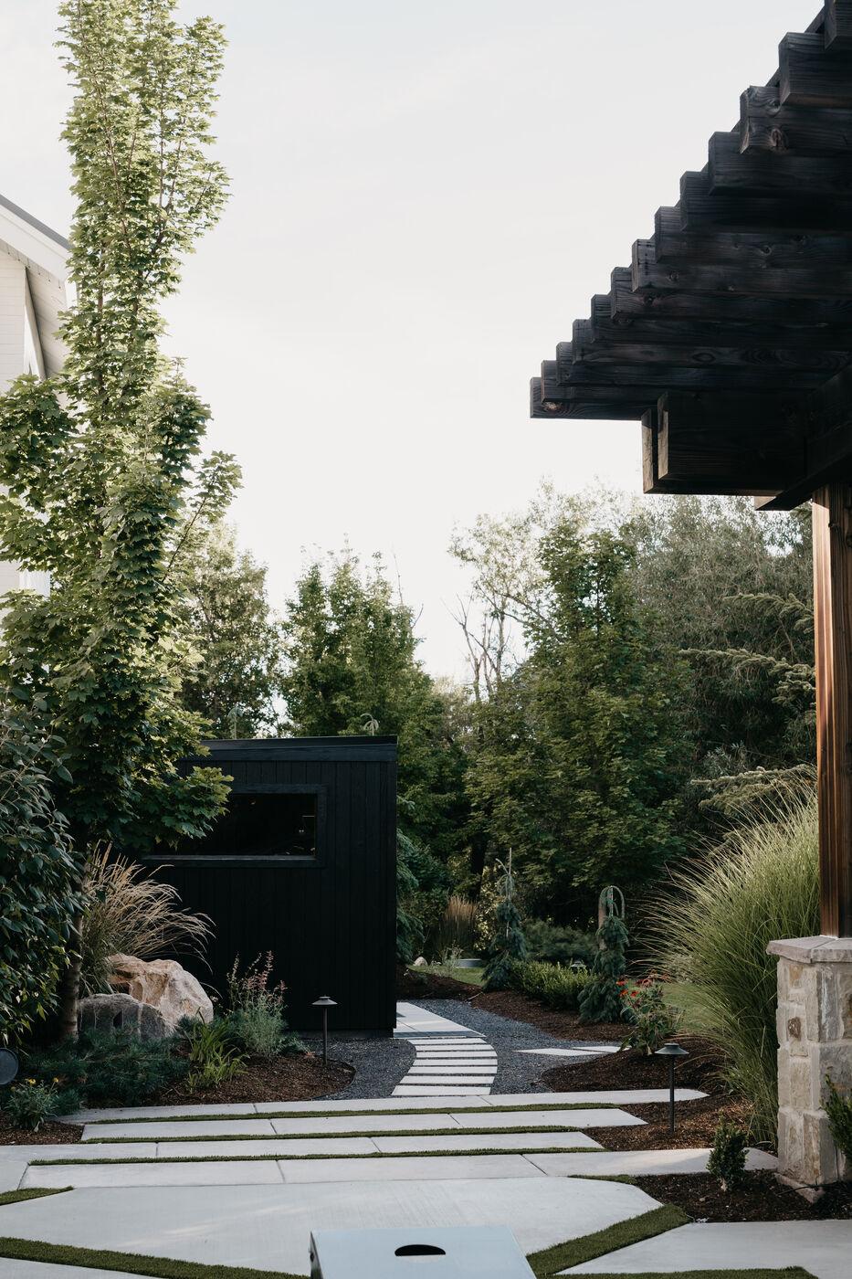 A flagstone path running under a timber pergola beside a blackened-timber structure