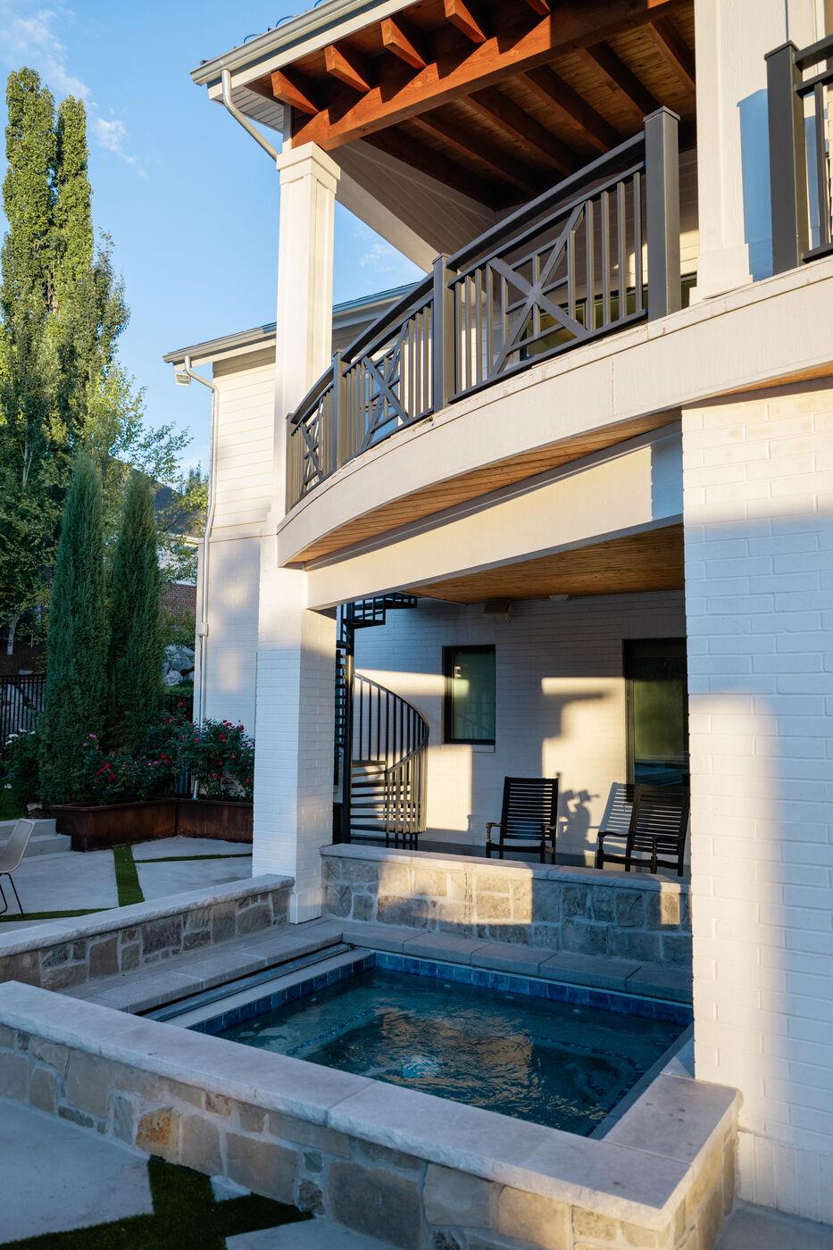 A raised spa set into stone coping below a two-storey balcony
