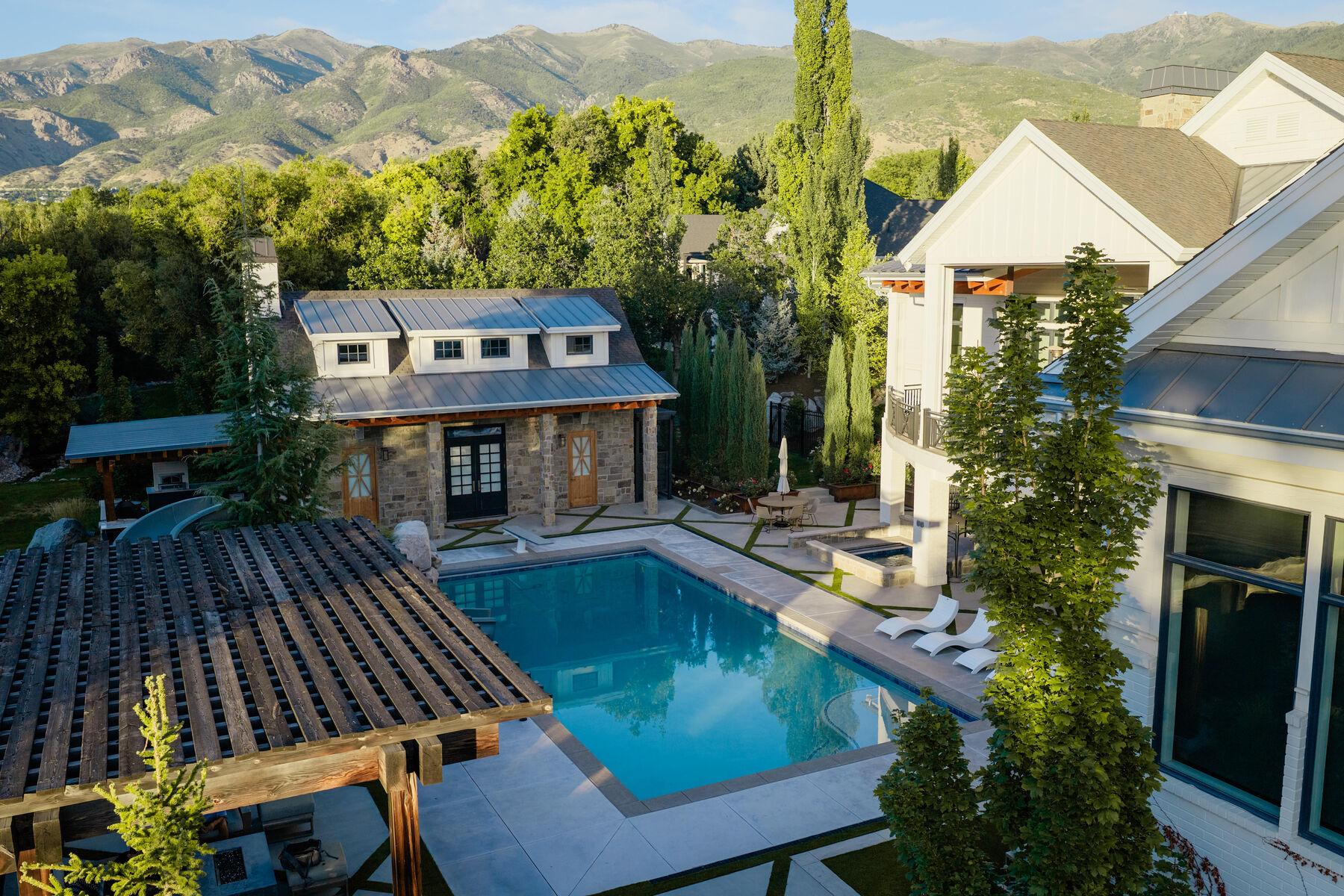 A pool with a stone pool house and slatted timber pergola, mountains rising behind