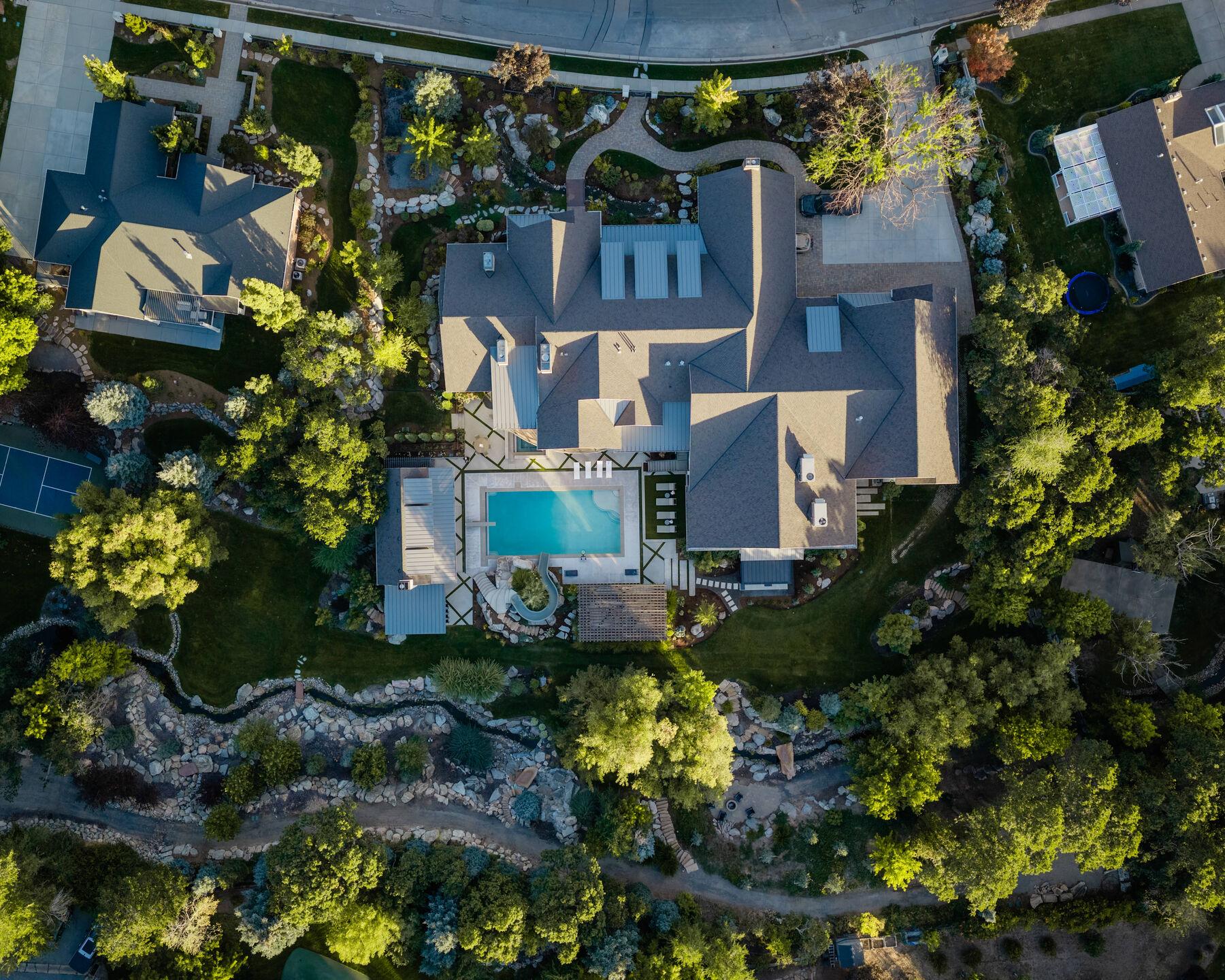 Overhead view of the whole property — pool, stream, and mature planting under mixed roofs