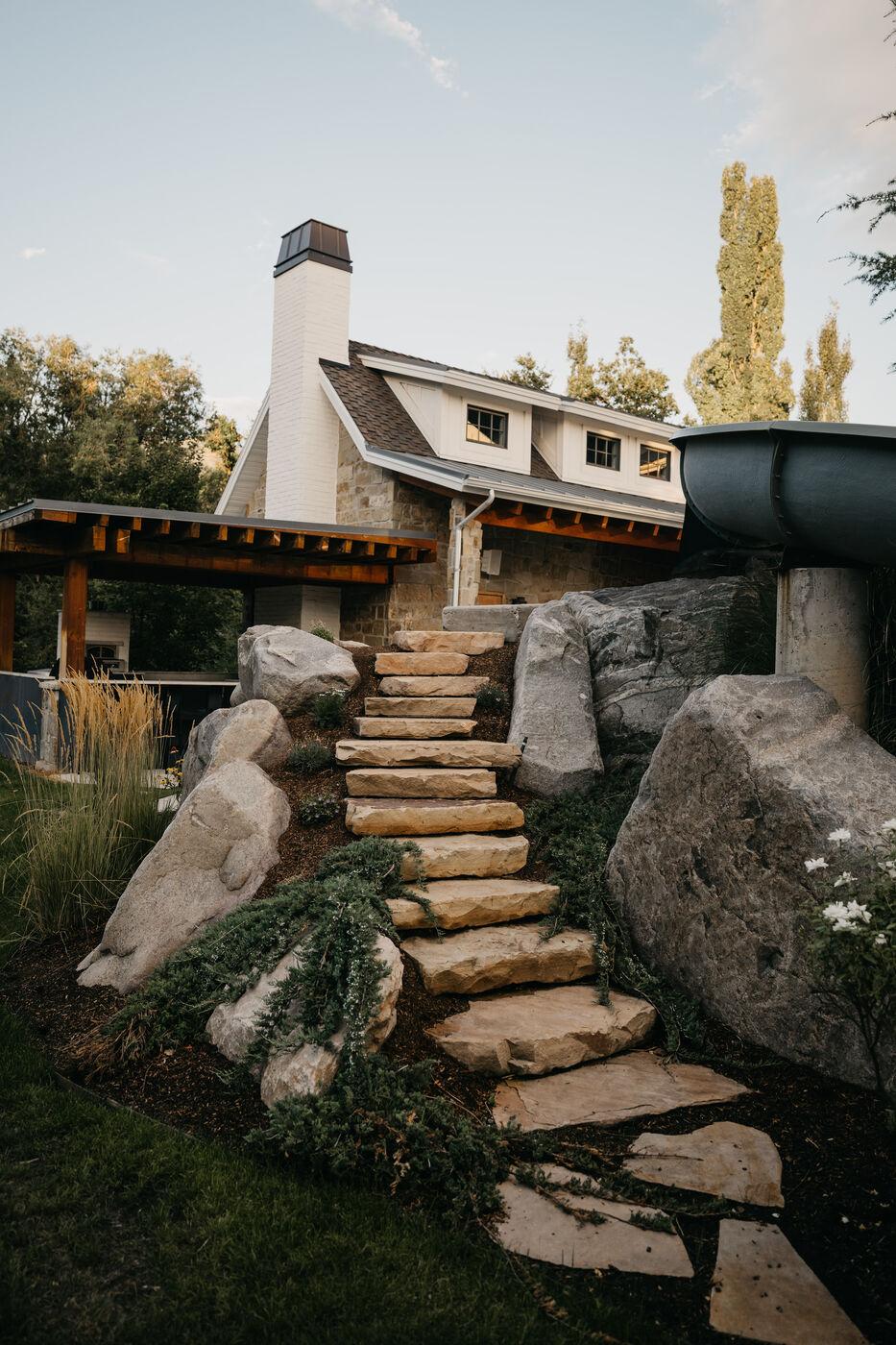 Stone slab steps climbing between set boulders to the house above
