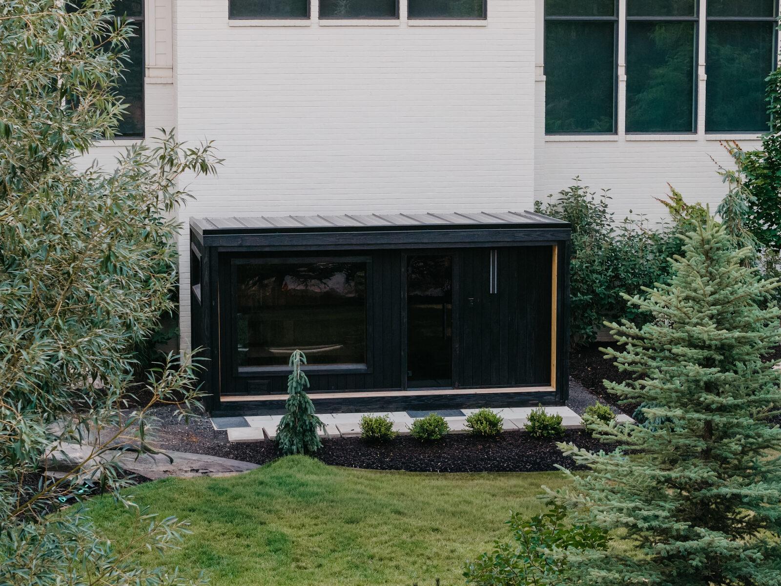 Clipped evergreen and mixed planting meeting a sod lawn beside a modern structure