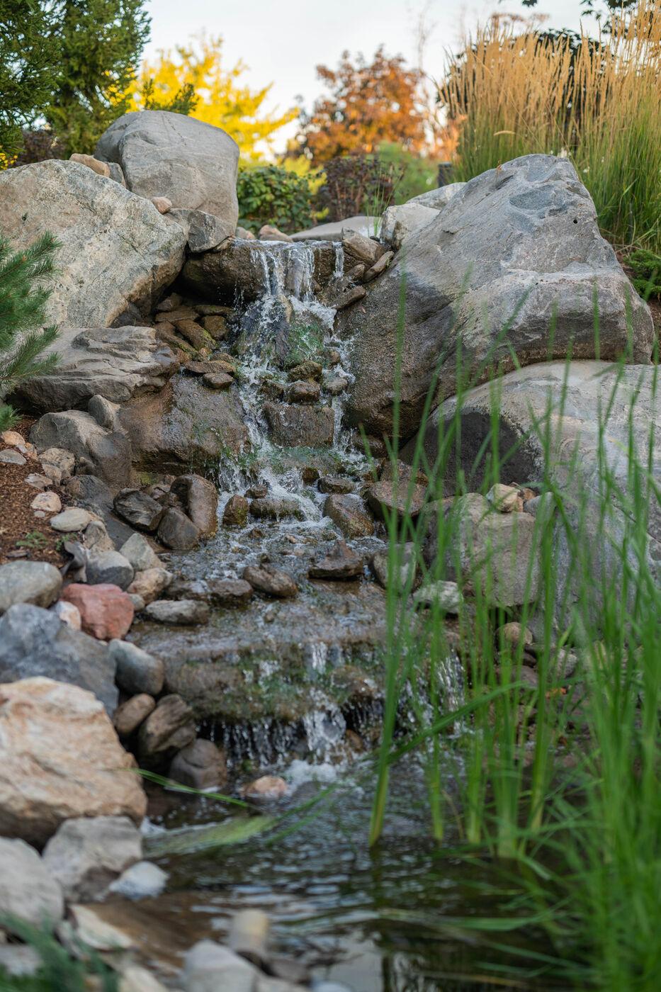 A boulder waterfall spilling into a planted margin