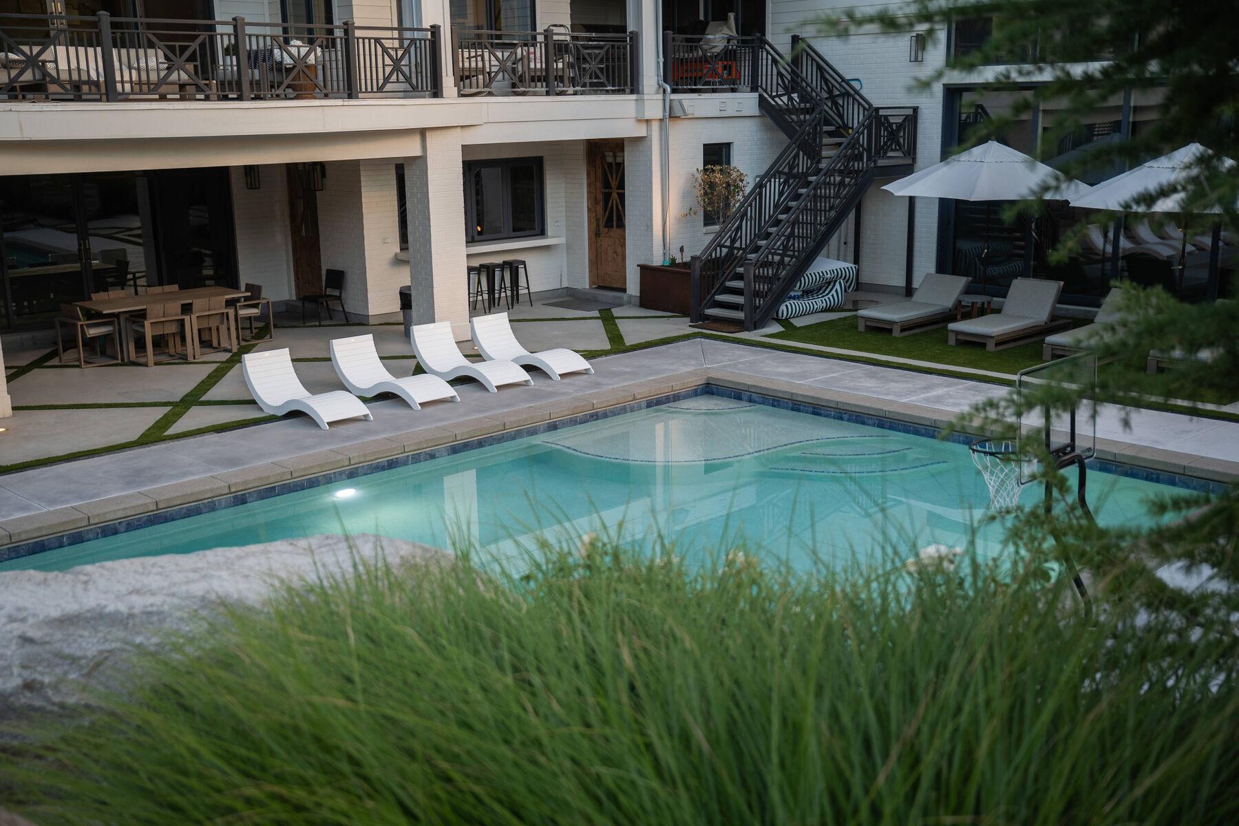 Ornamental grasses in the foreground of a pool deck lined with loungers