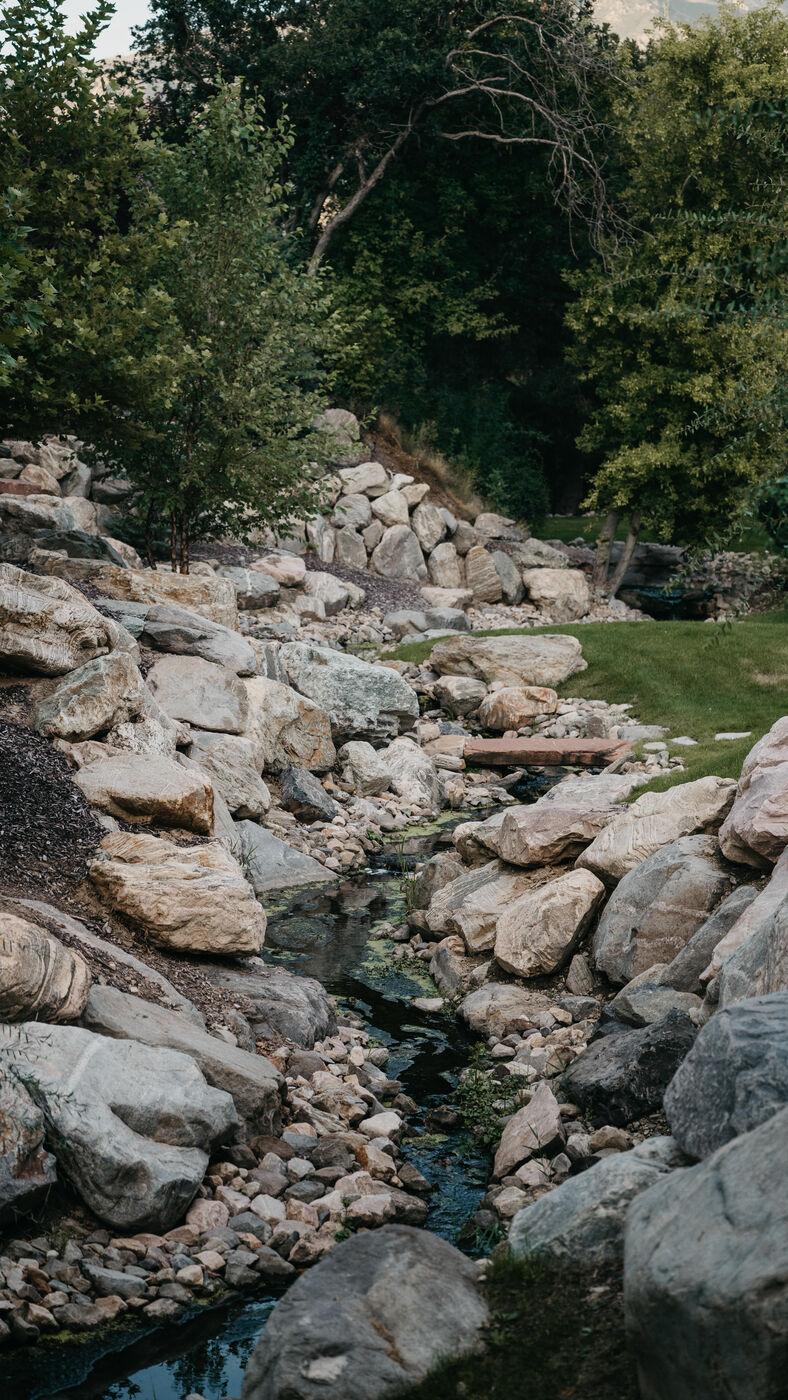 A boulder-set stream bed running between planting and lawn